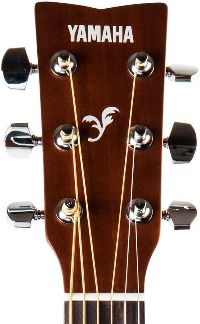 Close do headstock do violão Yamaha F 310 folk acústico natural. Madeira escura com acabamento fosco, logotipo Yamaha branco no topo, desenho decorativo abaixo do logo, 6 tarraxas cromadas com botões.