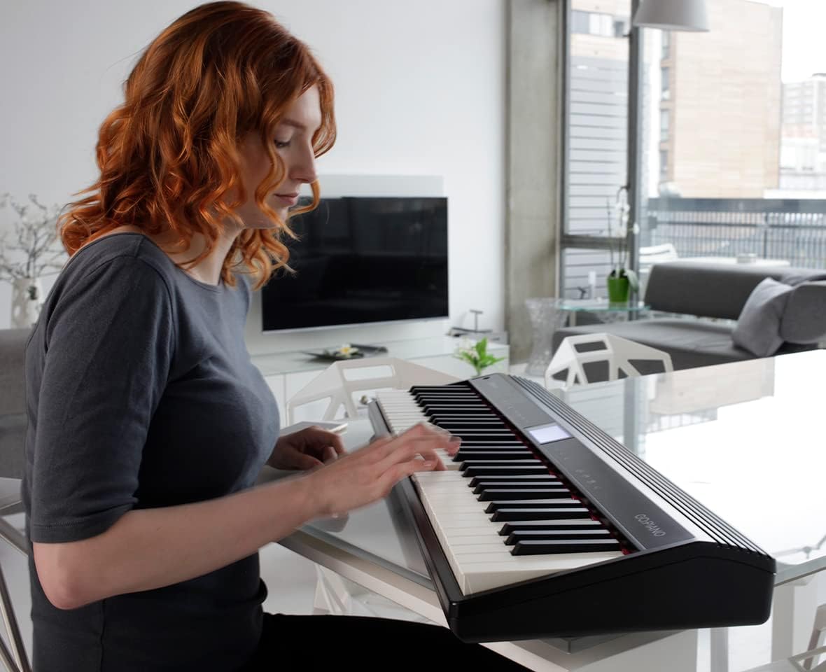 Mulher ruiva tocando teclado Roland GO:Piano GO-61P em ambiente moderno e iluminado, mostrando portabilidade e uso residencial.