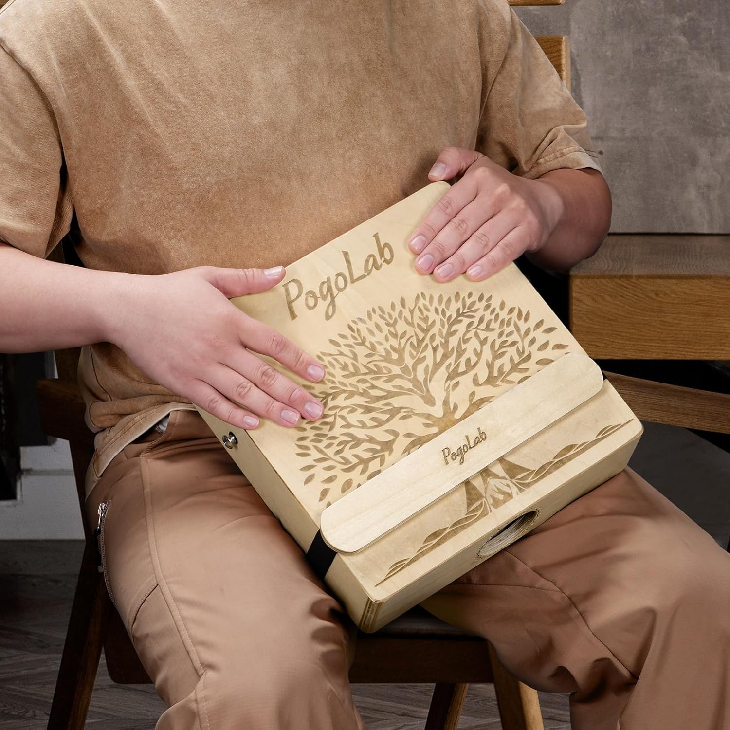 Pessoa tocando o cajon POGOLAB em madeira clara, mostrando ergonomia e uso prático