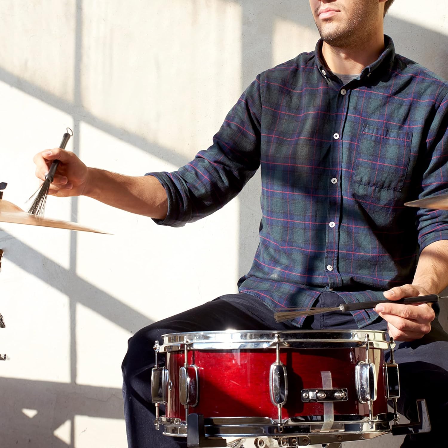 Músico usando escovas retráteis para bateria em ambiente iluminado naturalmente